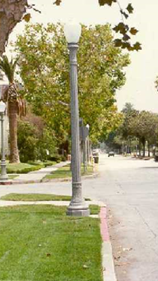Single spherical globe on a simple decorative concrete post near a sidewalk.