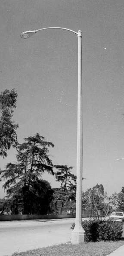 Simple concrete or metal light pole with a long, sweeping arched arm over a sidewalk.