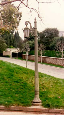 Color photo of a single lantern post situated along a park walkway.