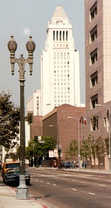 An ornate twin-lantern street lamp in the foreground with the iconic white tower of Los Angeles City Hall behind it.